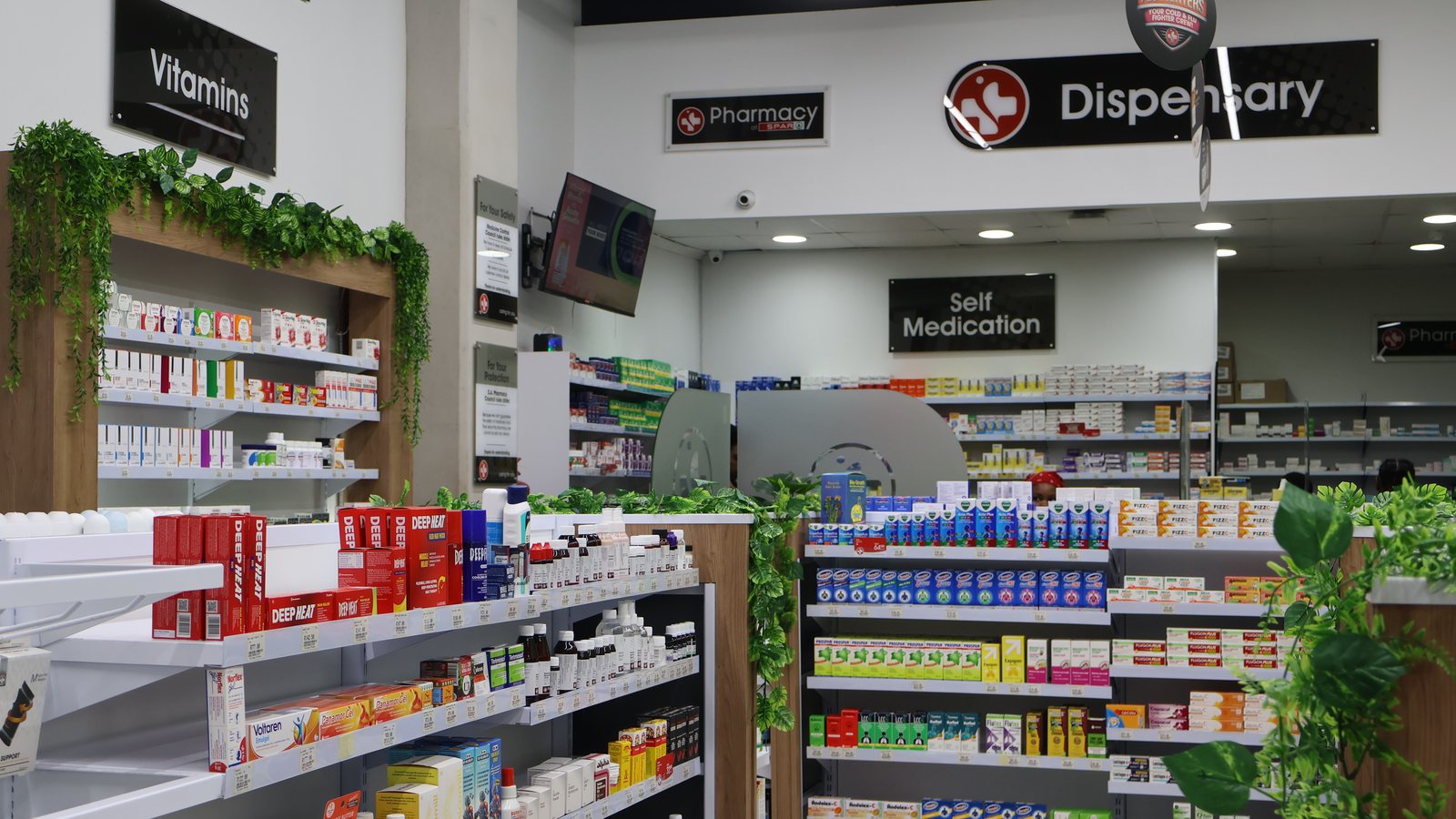 The pharmacy floor, with the dispensary counter ahead and the vitamin and self-medication aisles to either side